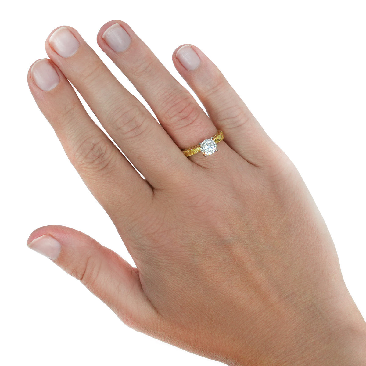 A yellow gold ring with a round-cut clear gemstone, shown worn on a person's ring finger against a plain white background. [lifestyle]