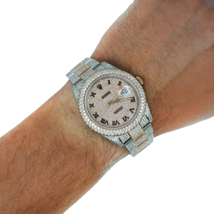 A two-tone silver and gold Rolex-style watch fully paved with clear stones, shown worn on a person's wrist against a white background. [lifestyle]