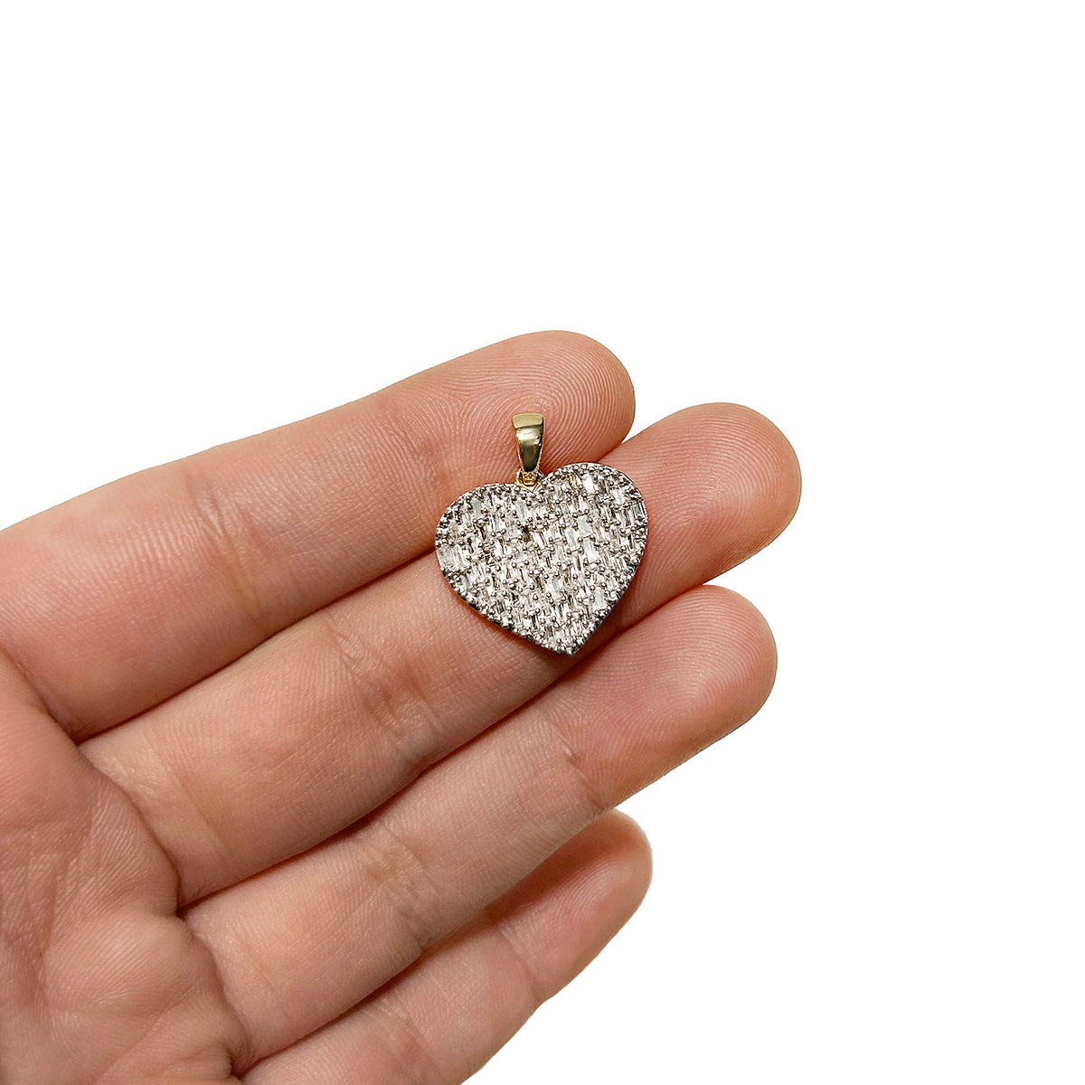 A heart-shaped pendant covered in small clear stones, held on a person's fingers against a plain white background. [lifestyle]