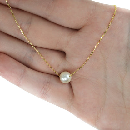 A delicate gold chain necklace with a single round white pearl pendant, displayed on an open hand against a white background. [lifestyle]