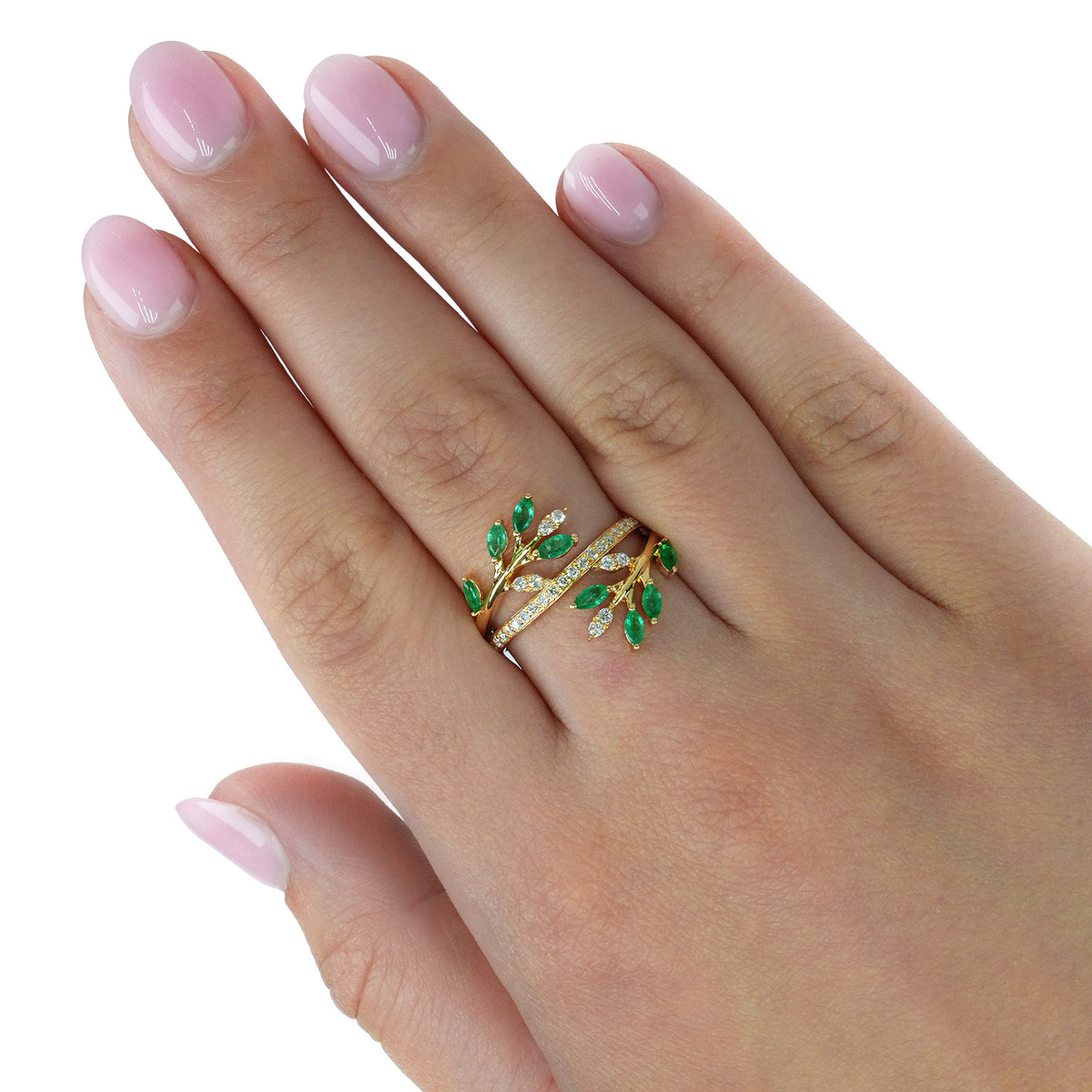 A close-up of a hand with light pink manicured nails wearing a gold wrap ring decorated with green leaf-shaped enamel and small clear stones. [lifestyle]