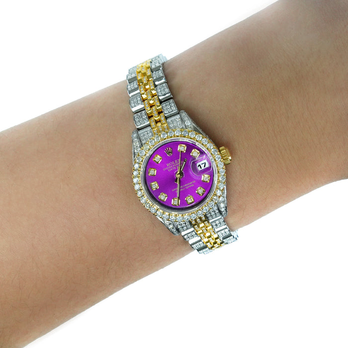 A two-tone Rolex watch with a purple dial, diamond-set bezel, and yellow and silver link bracelet, shown worn on a person's wrist against a white background. [lifestyle]