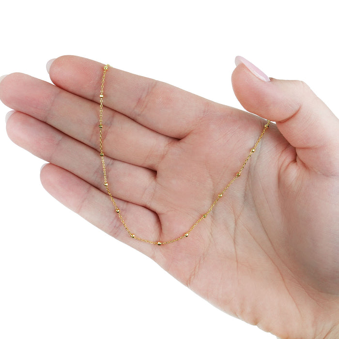 Gold chain necklace on a hand against a white background [lifestyle]