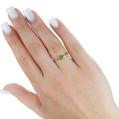 Gold ring with a green gemstone on a hand with white nail polish against a white background [lifestyle]