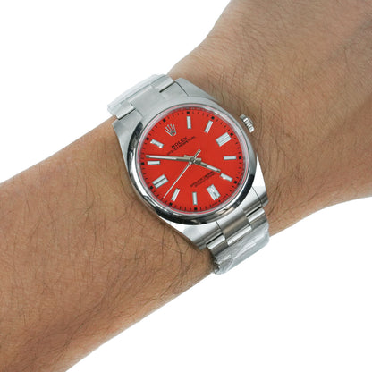 A Rolex Submariner watch with a vibrant red dial and a silver stainless steel bracelet, shown worn on a person's wrist against a plain white background. [lifestyle]