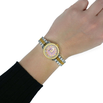 Hand wearing a watch with a blue face and gold accents on a white background [lifestyle]