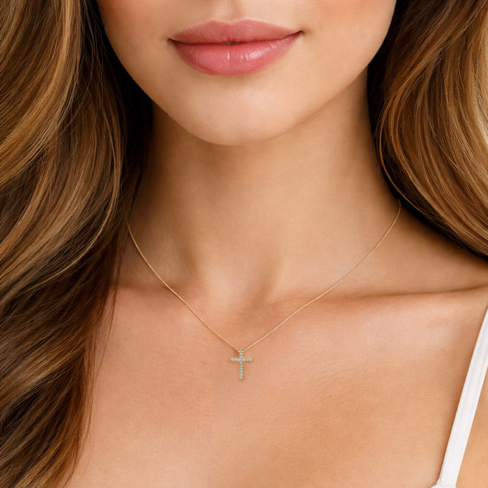 Close-up of a woman wearing a gold necklace with a cross pendant. [lifestyle]