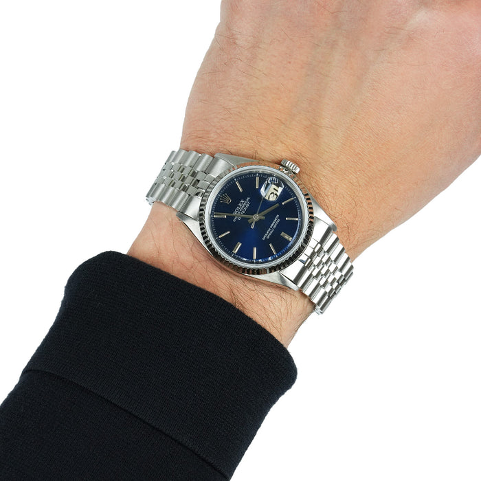 Silver watch with a blue face on a wrist against a white background [lifestyle]