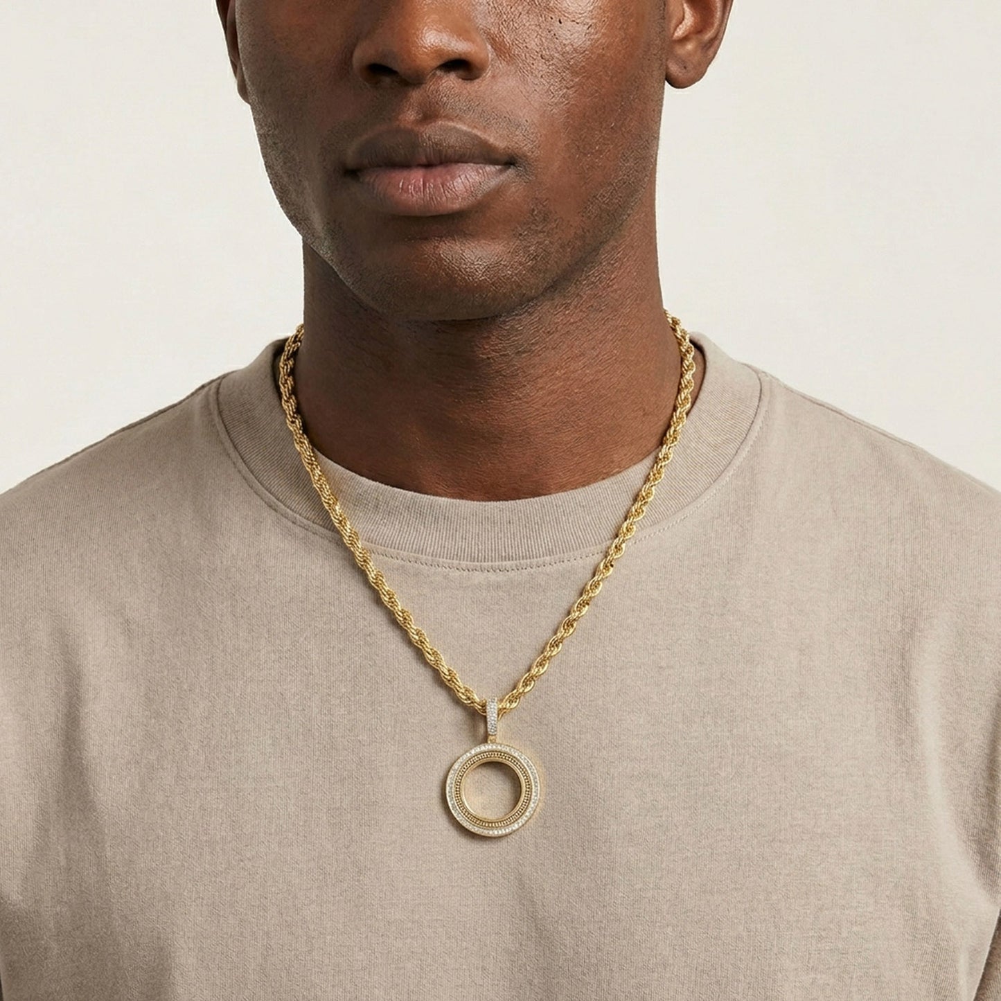 Man wearing a gold chain necklace with a pendant on a plain background [lifestyle]