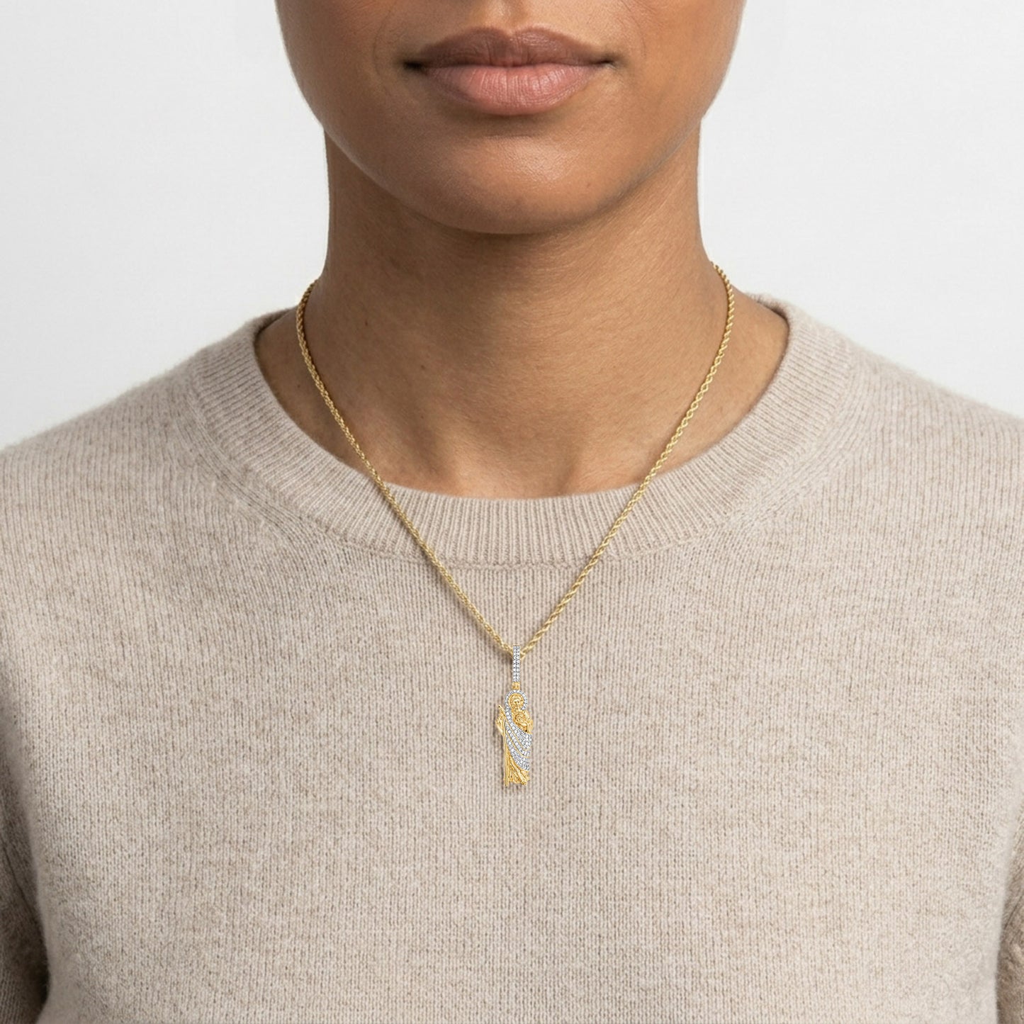 Person wearing a gold necklace with a pendant on a plain background [lifestyle]