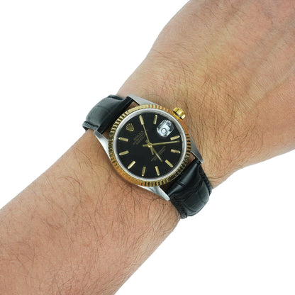 Wrist wearing a black and gold watch with a white background [lifestyle]