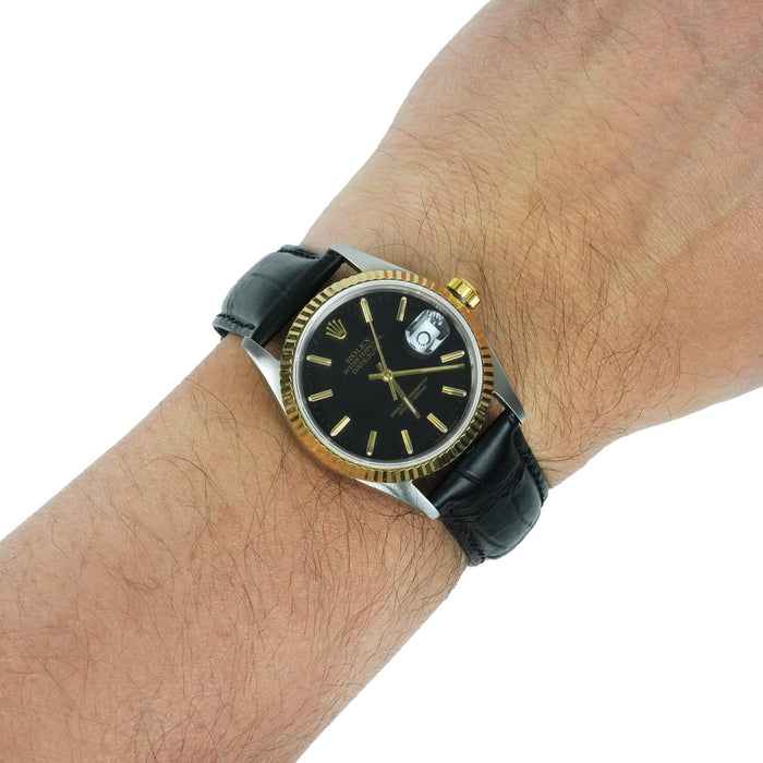 Wrist wearing a black and gold watch with a white background [lifestyle]