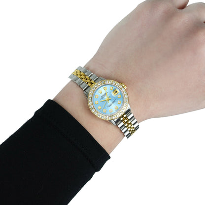 Gold and silver watch with a blue face on a wrist against a white background [lifestyle]