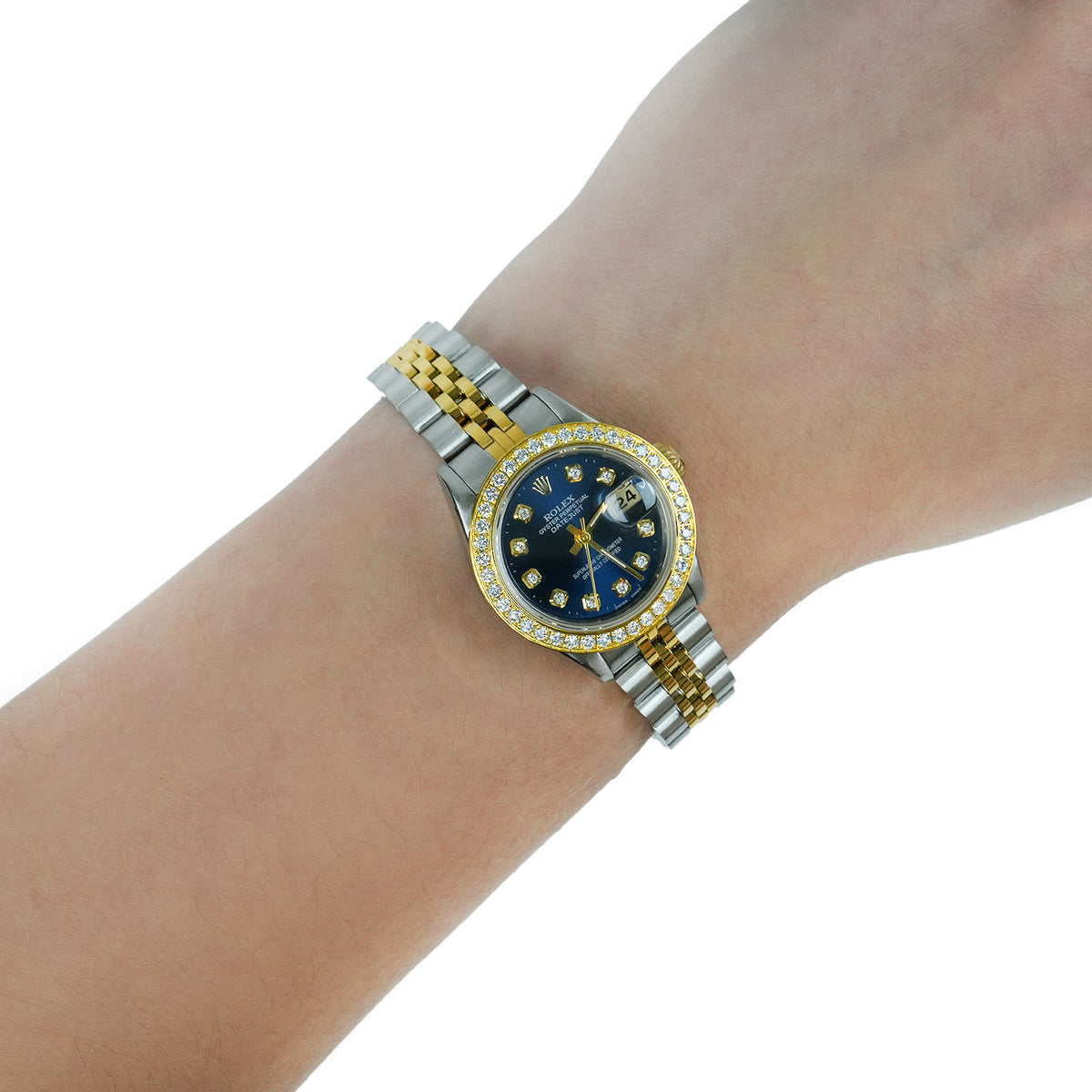 A two-tone stainless steel and yellow gold wristwatch with a blue dial and diamond bezel, shown worn on a person's wrist against a white background. [lifestyle]