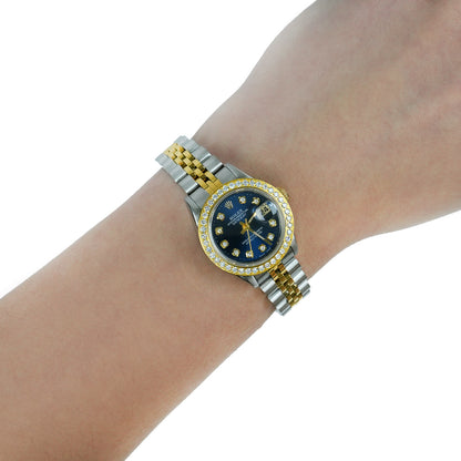 A two-tone stainless steel and yellow gold wristwatch with a blue dial and diamond bezel, shown worn on a person's wrist against a white background. [lifestyle]