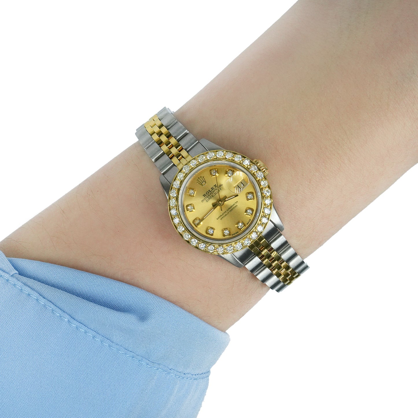 Gold and silver watch on a wrist with a light blue sleeve [lifestyle]