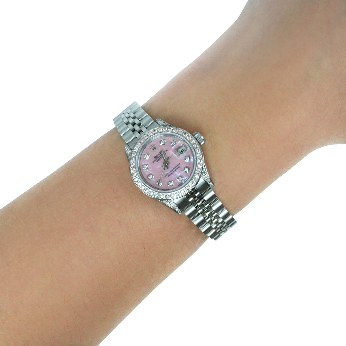 A silver-tone stainless steel watch with a pink mother-of-pearl dial and crystal hour markers, shown worn on a wrist against a white background. [lifestyle]