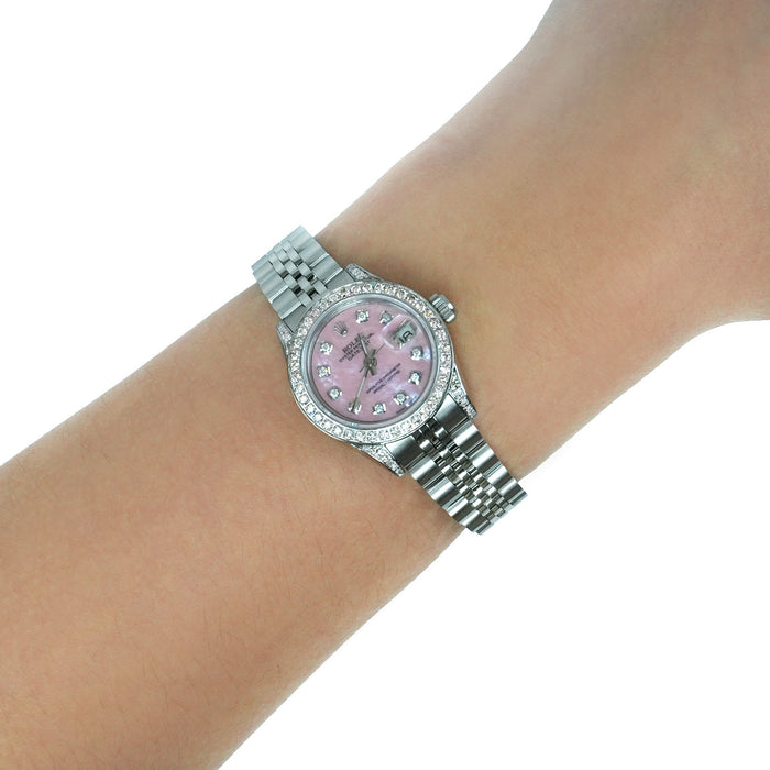 A silver-tone stainless steel watch with a pink mother-of-pearl dial and crystal hour markers, shown worn on a wrist against a white background. [lifestyle]
