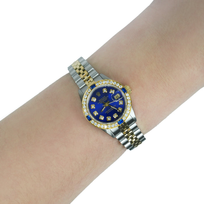 Two-tone watch with a blue face on a wrist against a white background [lifestyle]