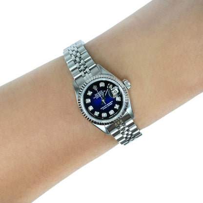 A silver Rolex Datejust watch with a blue dial and diamond hour markers, shown on a person's wrist against a white background. [lifestyle]