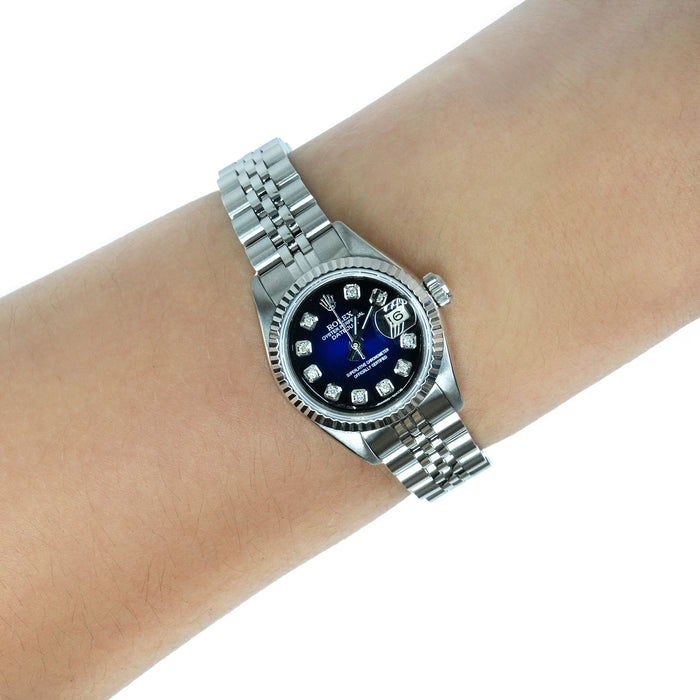 A silver Rolex Datejust watch with a blue dial and diamond hour markers, shown on a person's wrist against a white background. [lifestyle]