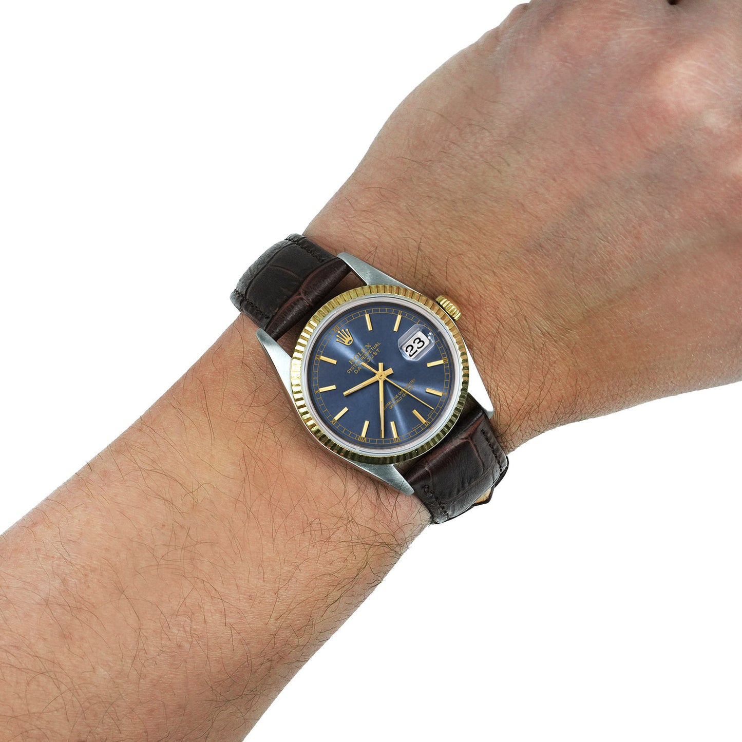 Wrist wearing a watch with a blue face and brown leather strap on a white background [lifestyle]