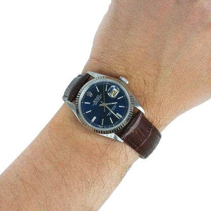 Wrist wearing a watch with a brown leather strap and blue dial on a white background [lifestyle]
