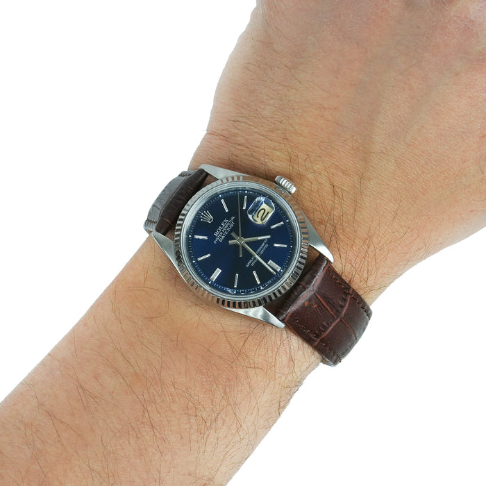 Wrist wearing a watch with a brown leather strap and blue dial on a white background [lifestyle]