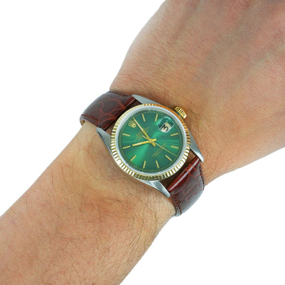 Wrist wearing a watch with a green face and brown leather strap on a white background [lifestyle]