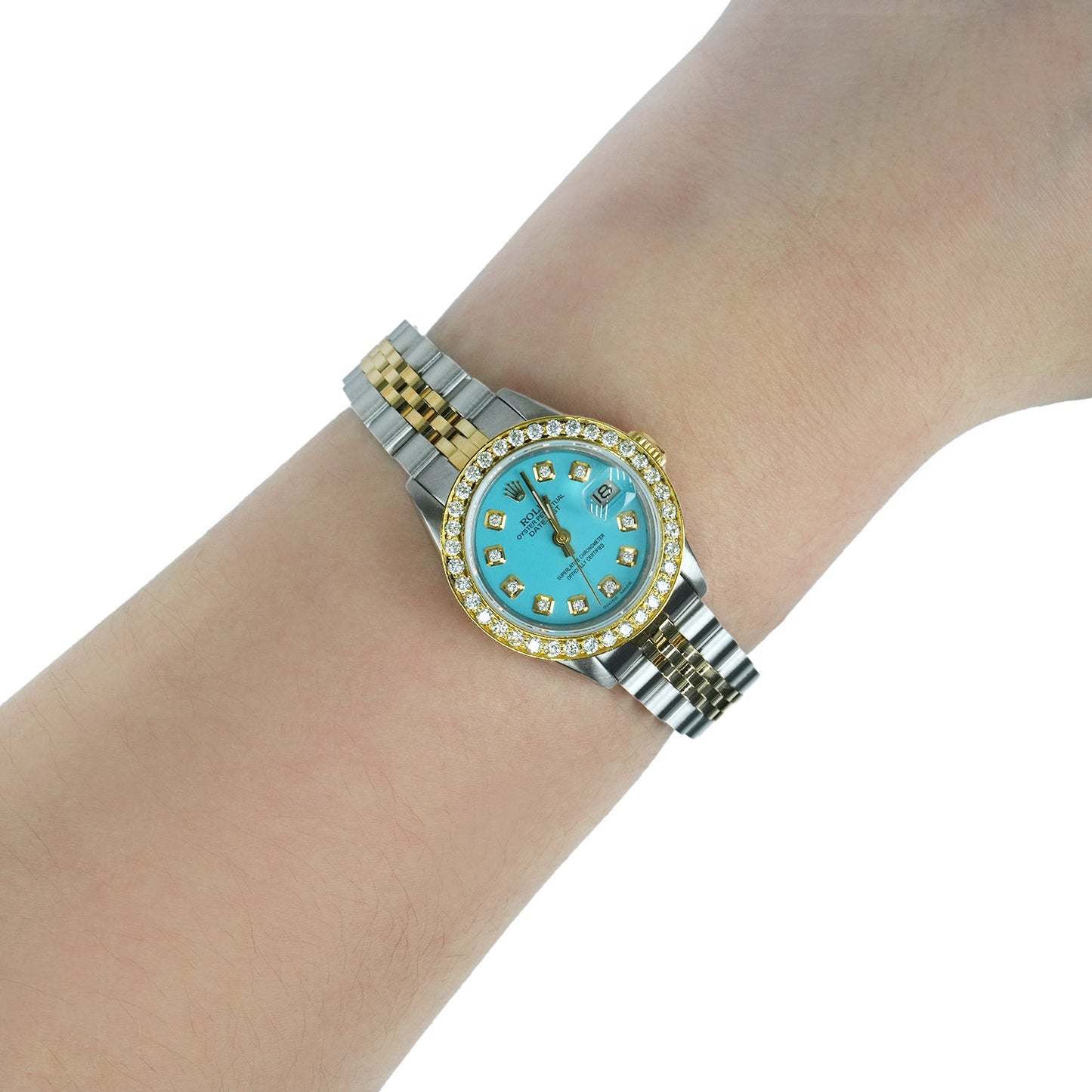 Gold and silver watch with a turquoise face on a wrist against a white background [lifestyle]