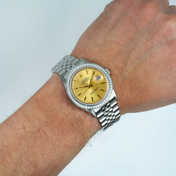 Silver watch with a gold face on a wrist against a light gray background [lifestyle]