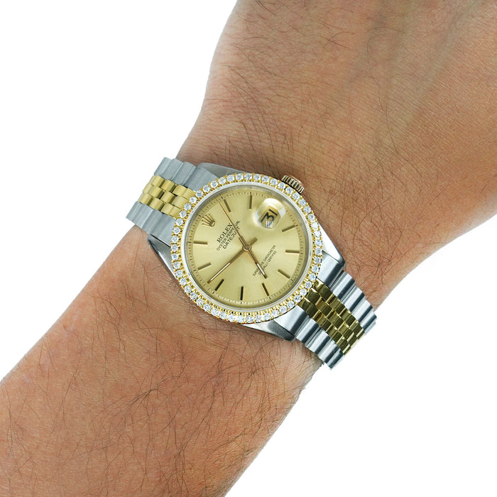 A Rolex Datejust watch with a gold dial, gold and silver two-tone metal bracelet, and a bezel set with small diamonds, shown worn on a person's wrist against a white background. [lifestyle]