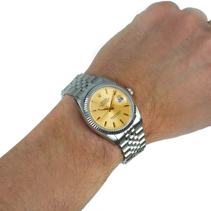 Silver watch with a gold face on a wrist against a white background [lifestyle]