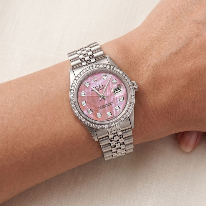 Silver watch with a pink face on a wrist against a neutral background [lifestyle]