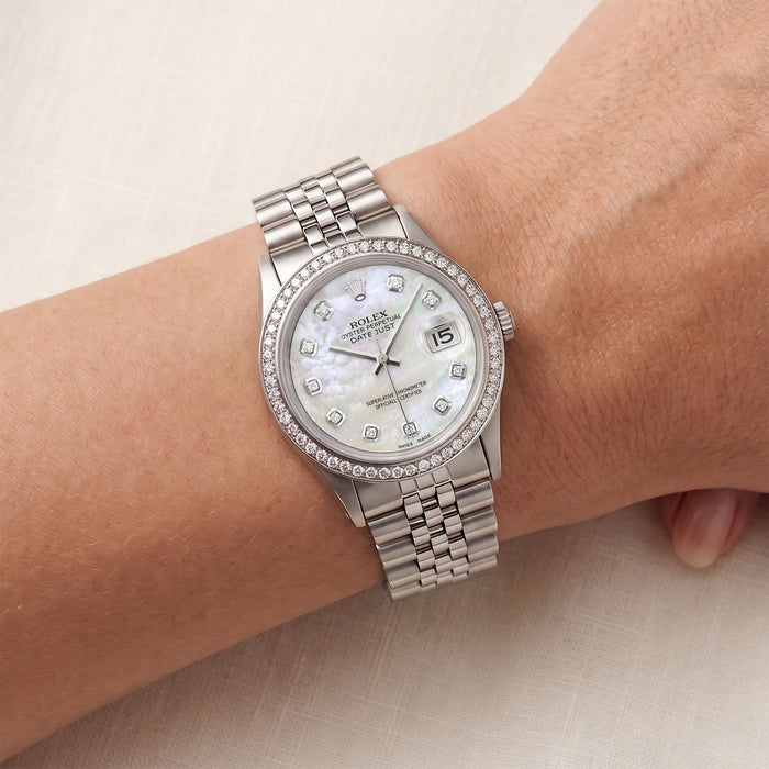 Silver wristwatch with diamond bezel on a wrist against a neutral background [lifestyle]