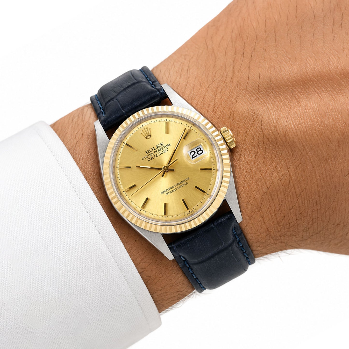 Gold watch with a blue strap on a wrist, wearing a white shirt. [lifestyle]
