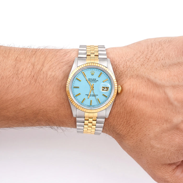 Two-tone watch with blue face on a wrist against a white background [lifestyle]