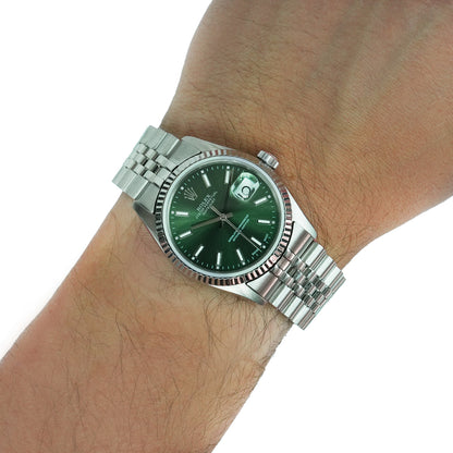 Silver watch with a green face on a wrist against a white background [lifestyle]