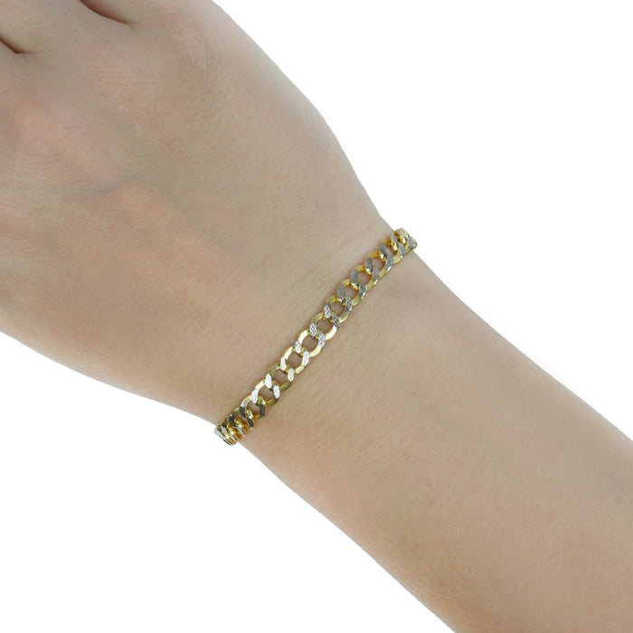 A gold-toned curb link bracelet worn on a person's wrist, shown against a plain white background. [lifestyle]