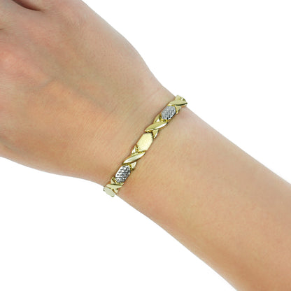 A gold and silver two-tone leaf-patterned bracelet worn on a person's wrist, shown against a plain white background. [lifestyle]