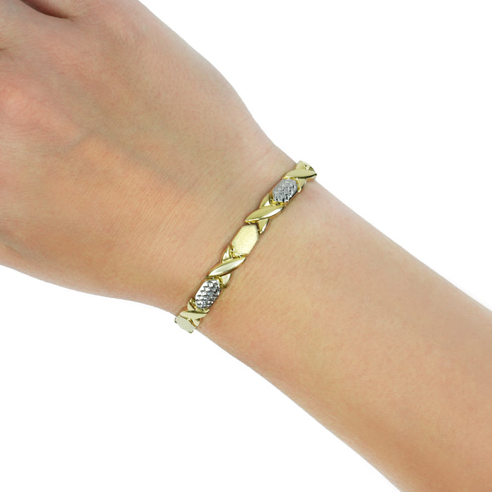 A gold and silver two-tone leaf-patterned bracelet worn on a person's wrist, shown against a plain white background. [lifestyle]