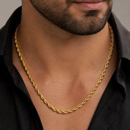 A close-up of a man wearing a thick, twisted gold chain necklace over a black collared shirt. [lifestyle]