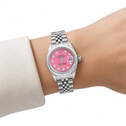 A Rolex Datejust watch with a pink dial and silver stainless steel bracelet, shown on a model's wrist wearing a light-colored cuff. [lifestyle]