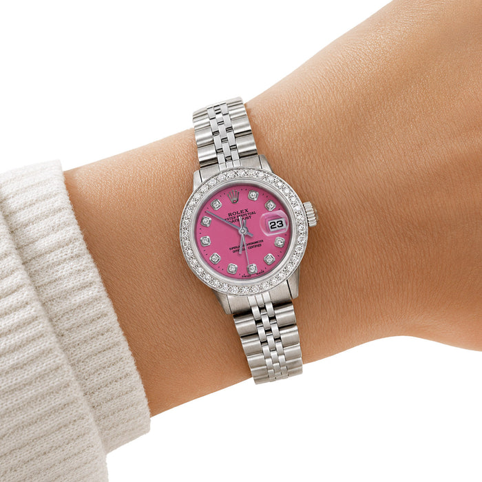 A Rolex Lady Day watch with a pink dial and diamond-set bezel, shown worn on a person's wrist. [lifestyle]