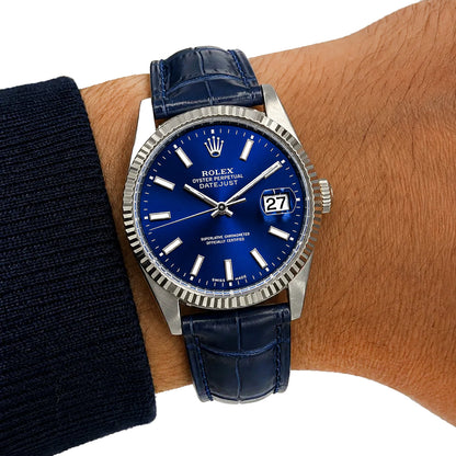 A Rolex Datejust wristwatch with a deep blue dial and matching blue leather strap, shown worn on a person's wrist against a white background. [lifestyle]
