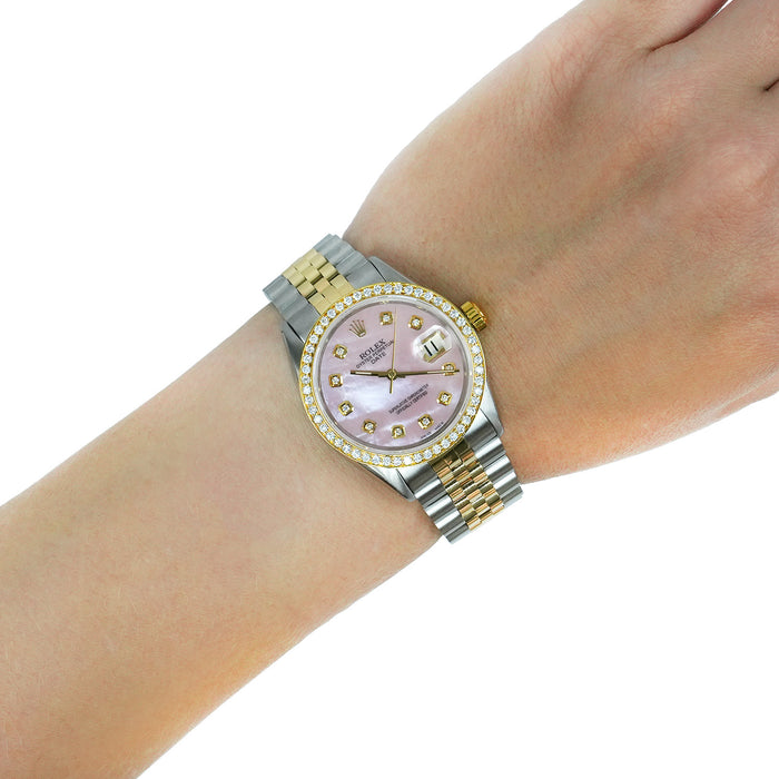 A Rolex Datejust watch with a pink mother-of-pearl dial, diamond-set bezel, and two-tone silver and gold stainless steel Oyster bracelet, shown worn on a wrist against a white background. [lifestyle]