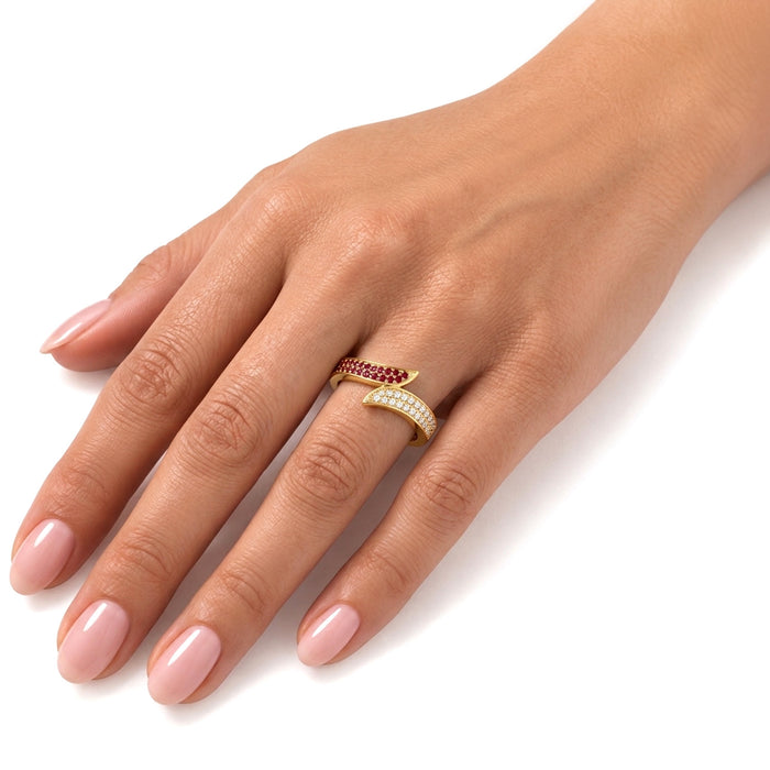 A close-up of a hand wearing two slim gold rings. One ring features a row of small red stones, and the other features a row of small clear stones. [lifestyle]