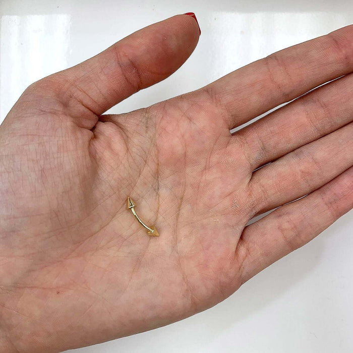 14k gold eyebrow spike barbell held in hand, featuring a high-polish finish and sleek design.