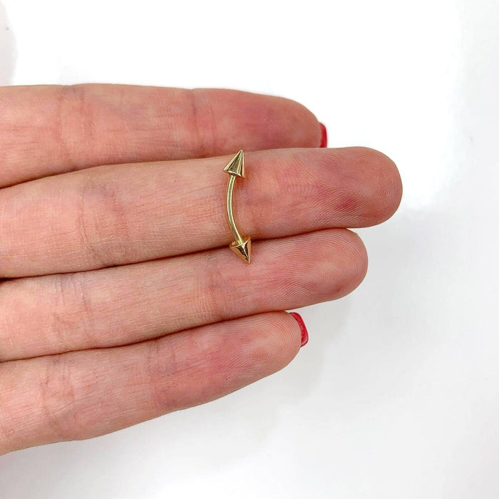 14k gold eyebrow spike barbell held in hand, featuring pointed ends and a sleek design for modern piercings.