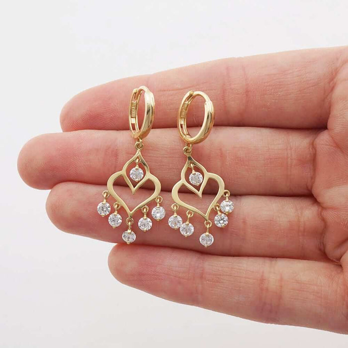 14k gold chandelier huggie hoop earrings in yellow gold with sparkling CZ stones elegantly displayed on a hand.